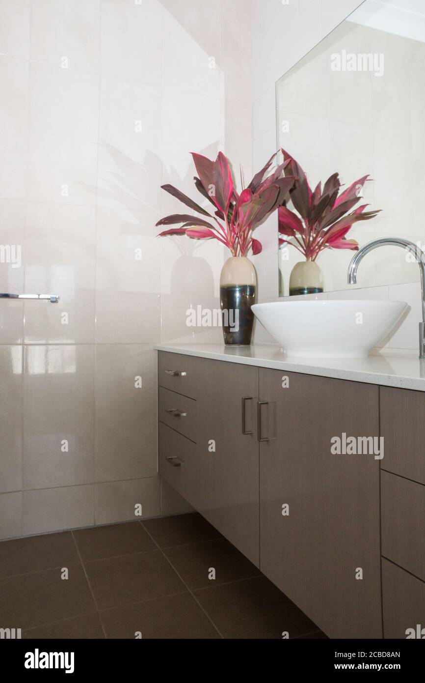 Bagno privato con panca in pietra su unità vanity e piastrellata pareti e pavimento in una nuova casa Foto Stock