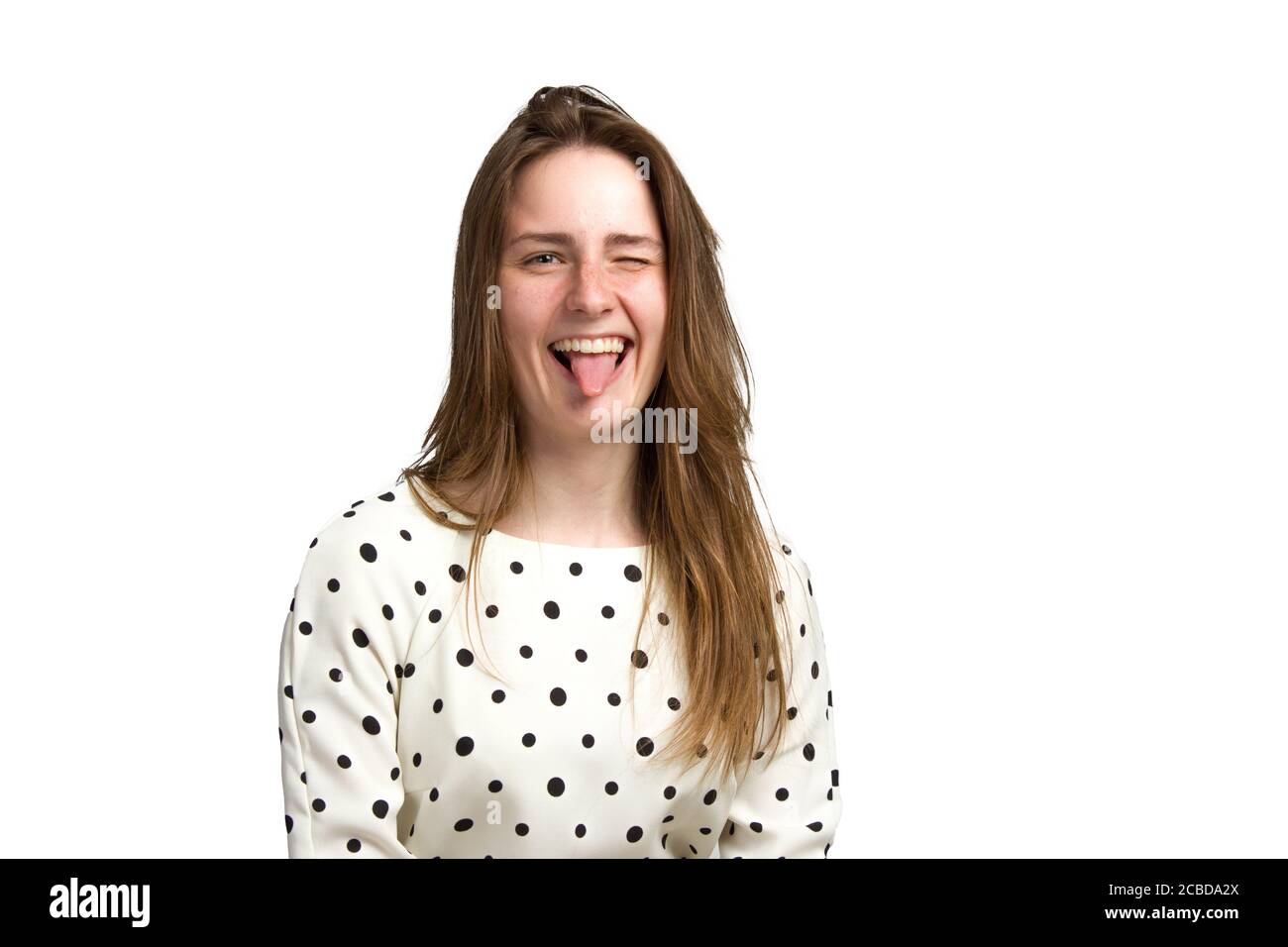 una giovane donna in un abito bianco a pois. Stacca la lingua, isolata in bianco Foto Stock