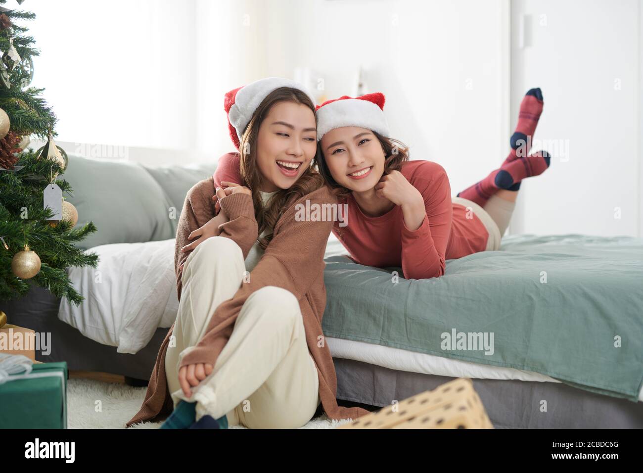 Due belle ragazze vicino all'albero di Natale in attesa di doni Foto Stock
