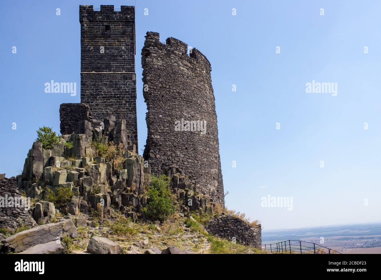 Ruines del castello di Hazmburk in cima alla cima della catena montuosa di ceske stredohori. Vista sulla torre bianca, le rocce e le pareti. Foto Stock