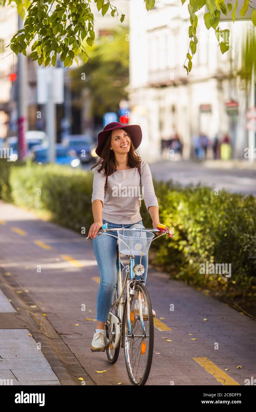 Una giovane donna felice sta viaggiando in bicicletta sul Strade a Budapest in giornata di sole Foto Stock