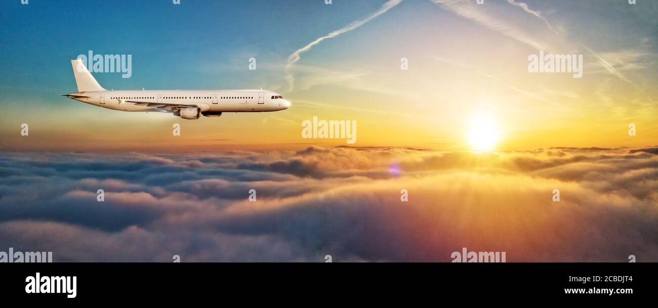 Aereo commerciale jetliner volare sopra le nuvole in bella luce del tramonto, vista laterale. Concetto di viaggio e di business. Foto Stock