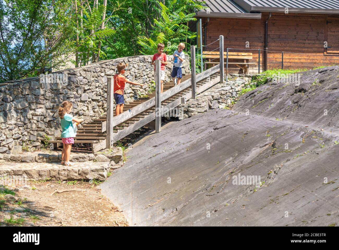 Bambini che guardano figure e scene di incisioni rupestri, Parco Nazionale Naquane, Capo di Ponte, Valcamonica, Lombardia, Italia Foto Stock