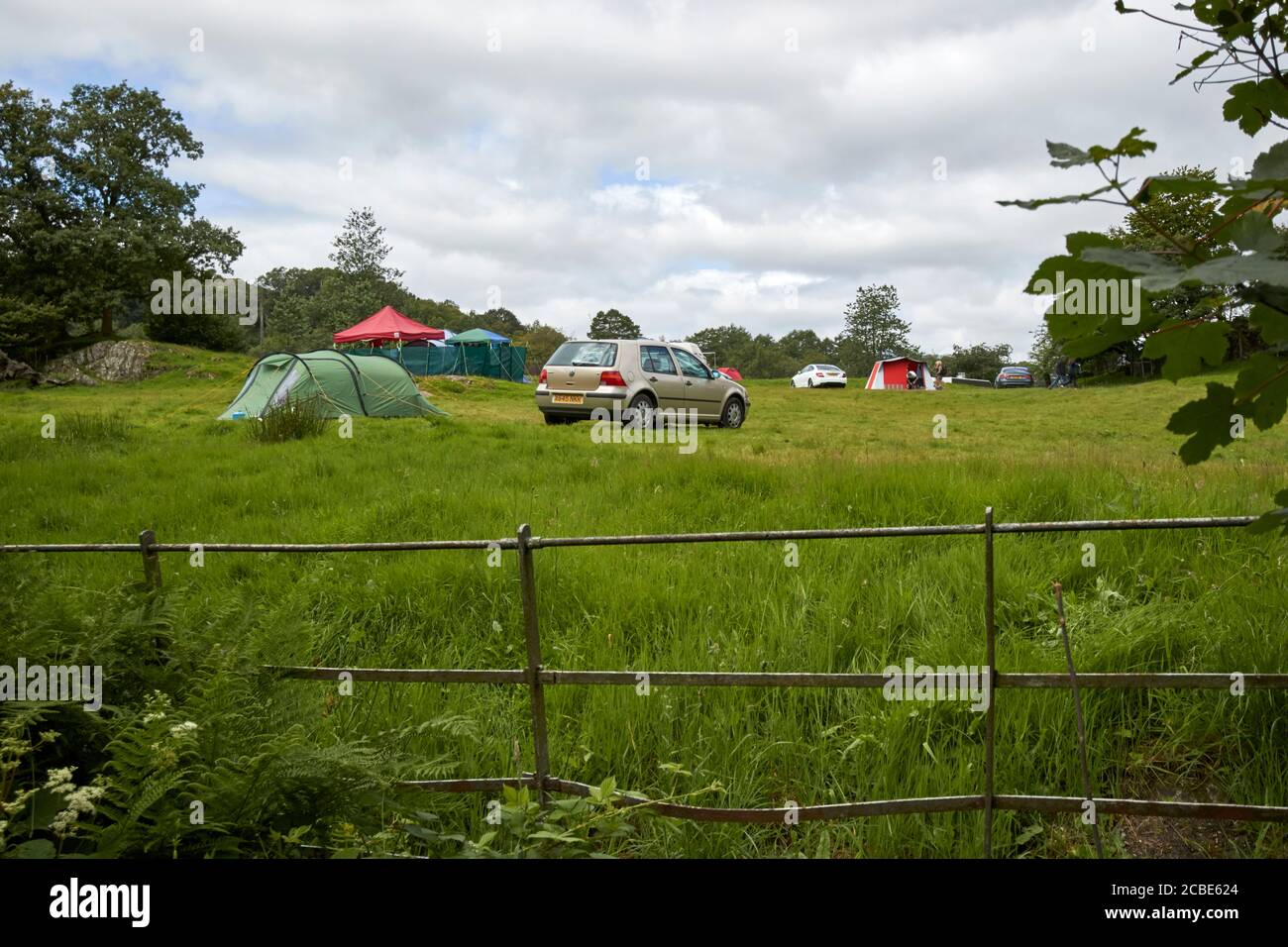 auto e tende in un campeggio agricolo con persone camping vicino loughrigg lake district cumbria inghilterra uk Foto Stock