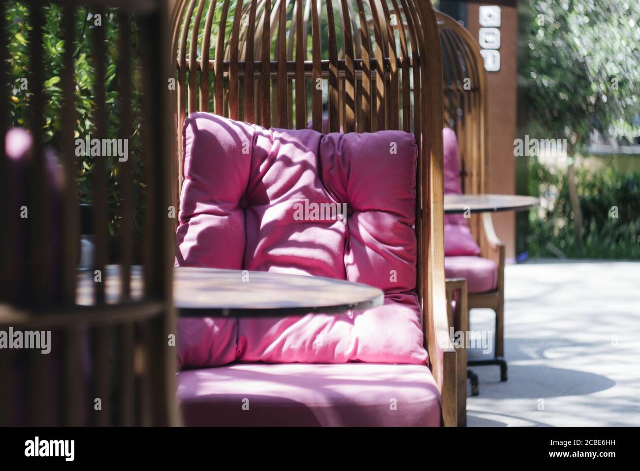 sedia in vimini con cuscini rosa su una veranda estiva in un caffè Foto Stock