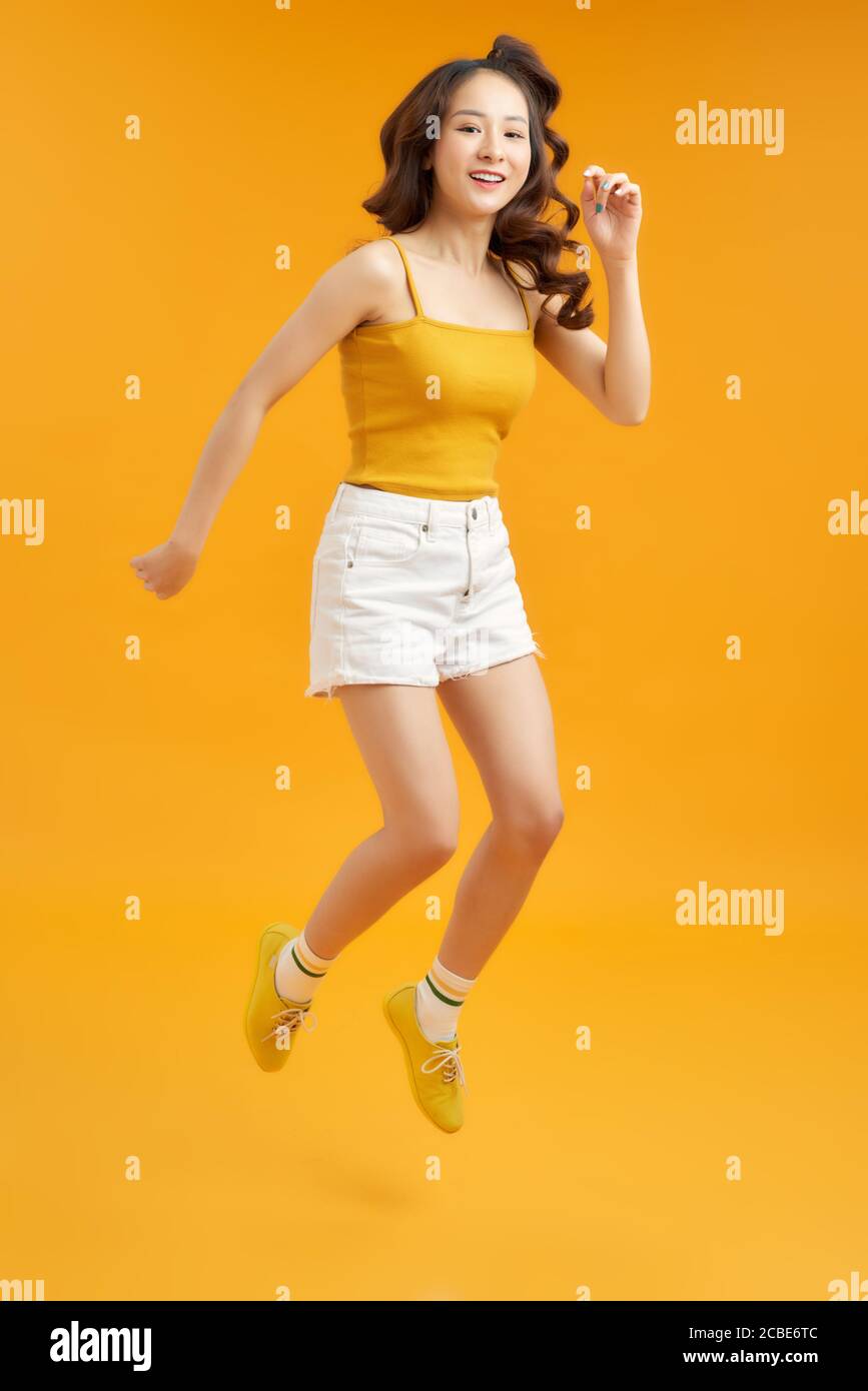 Foto girata a tutta lunghezza del corpo di eccitata estatica bella ragazza attraente isolato su sfondo giallo Foto Stock