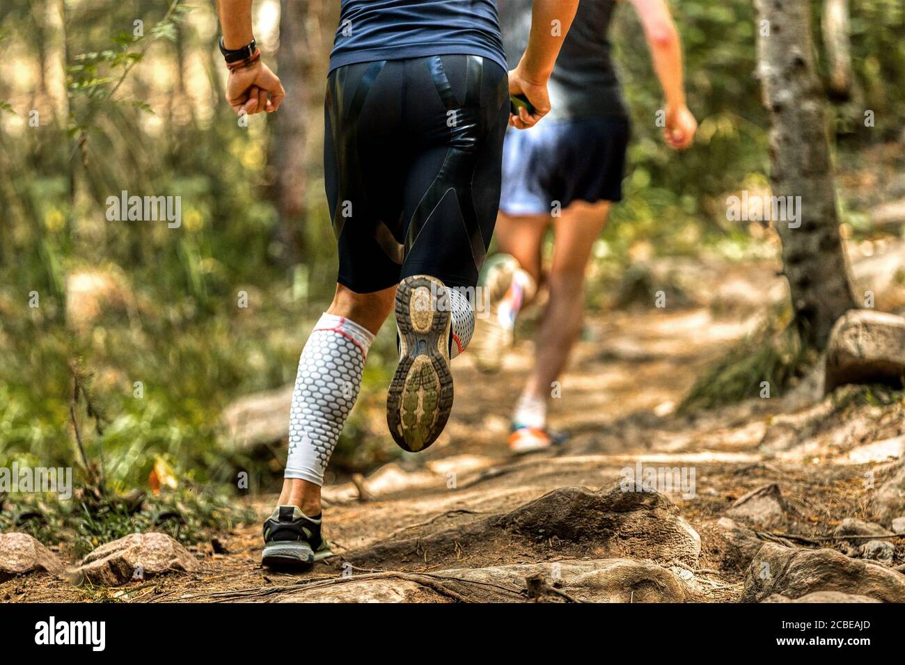 indietro uomo runner in calze a compressione running pietre sentiero Foto Stock
