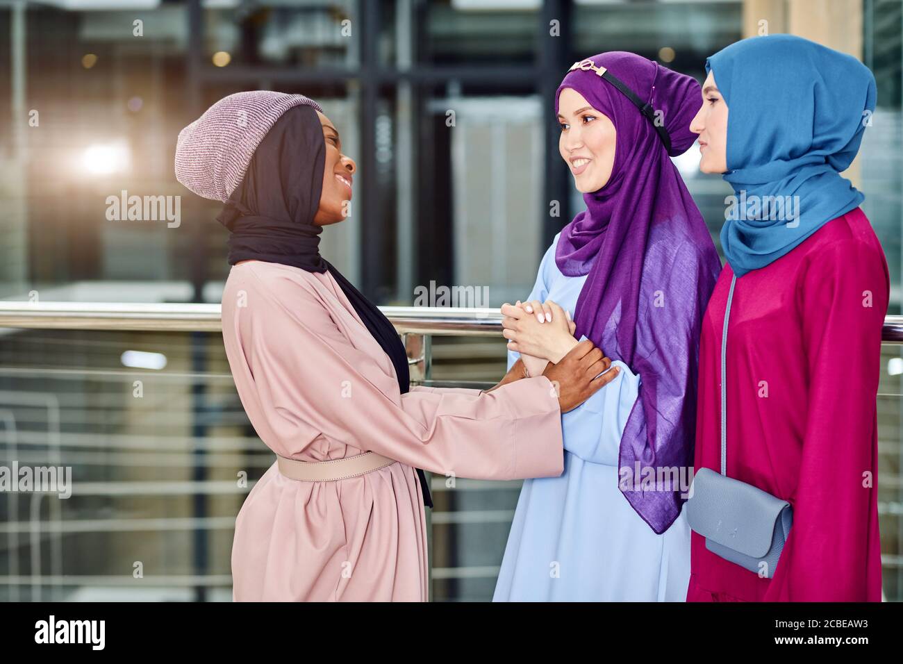 Ritratto di gruppo multirazziale di donne musulmane vestite in nazionale abiti e fiabe di colori brillanti che parlano insieme in amichevole maner in piedi Foto Stock
