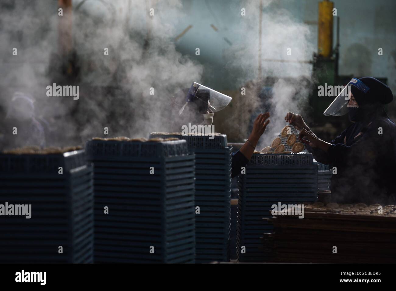 (200813) -- GIAVA OCCIDENTALE, 13 agosto 2020 (Xinhua) -- lavoratori che indossano maschere facciali e schermi facciali picchiano cracker a vapore da asciugare in una fabbrica di cracker a Depok, Giava Occidentale, Indonesia, 13 agosto 2020. L'Indonesia distribuirà l'assistenza al capitale circolante per 9 milioni di piccole e medie imprese (PMI) per aiutarli a rilanciare le imprese che sono state deluse dalla nuova pandemia del coronavirus, ha detto mercoledì un ministro. (Xinhua/Agung Kuncahya B.) Foto Stock