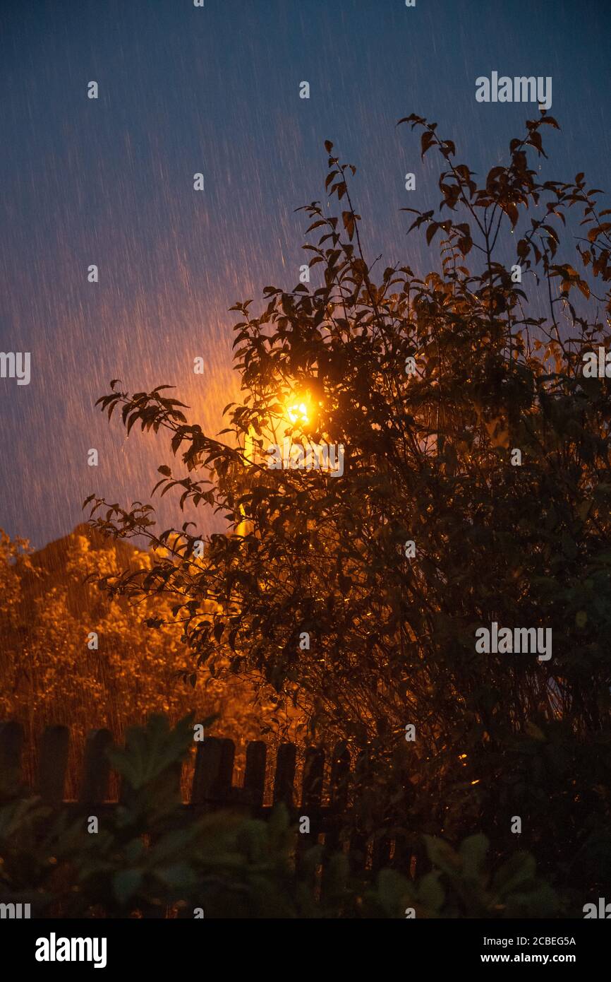 Pioggia torrenziale di notte illuminata da una lampada da strada durante una tempesta estiva nel Regno Unito. Foto Stock
