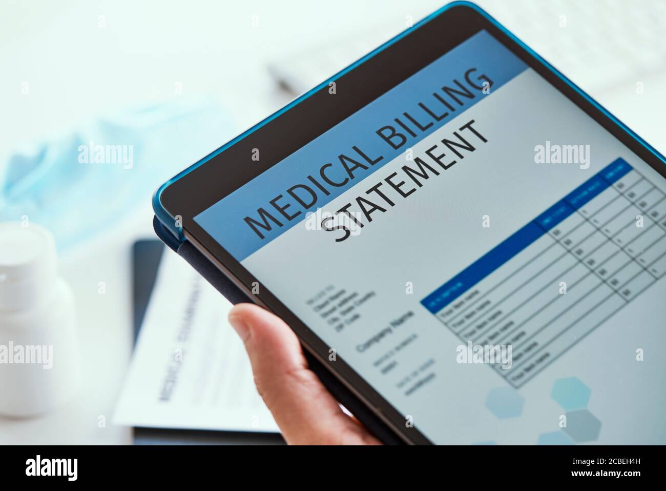 closeup di un medico caucasico, seduto alla sua scrivania d'ufficio, controllare una dichiarazione di fatturazione medica in un tablet digitale Foto Stock