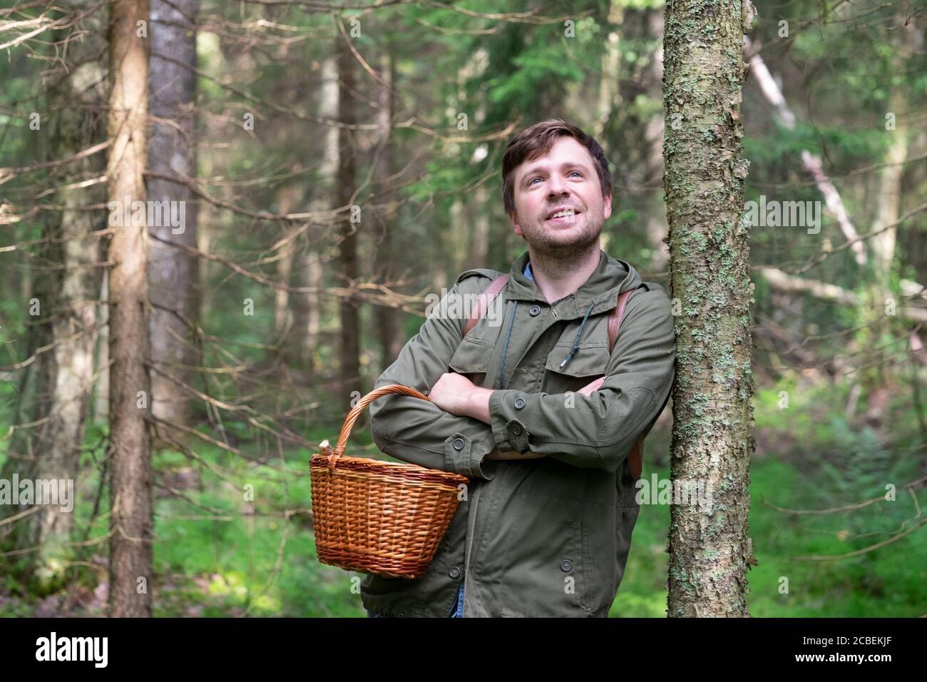 Uomo che cammina in piedi vicino albero in foresta riposando godendo il momento Foto Stock