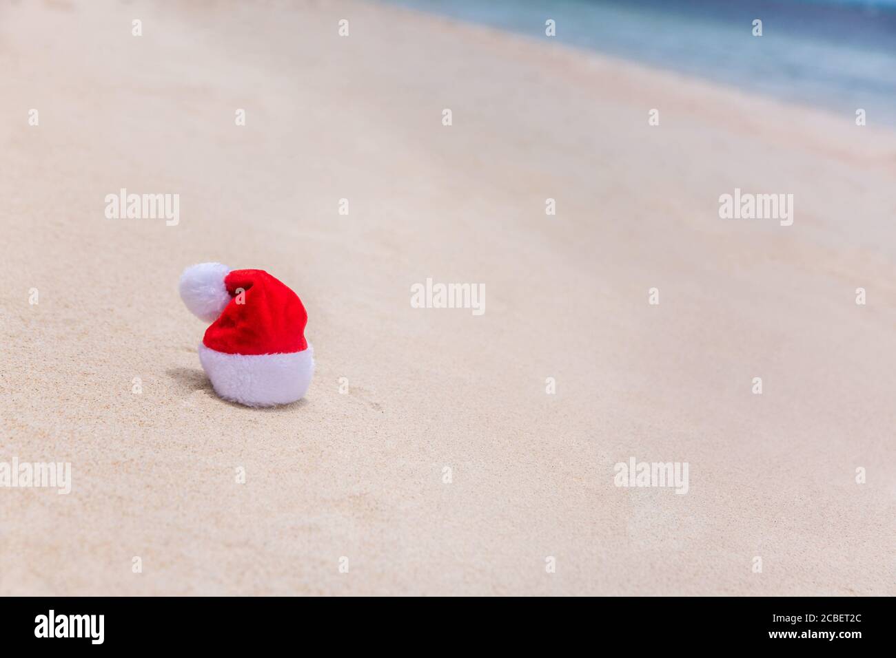 Cappello di Natale in sabbia su una spiaggia tropicale. Vacanza tropicale estate concetto Foto Stock