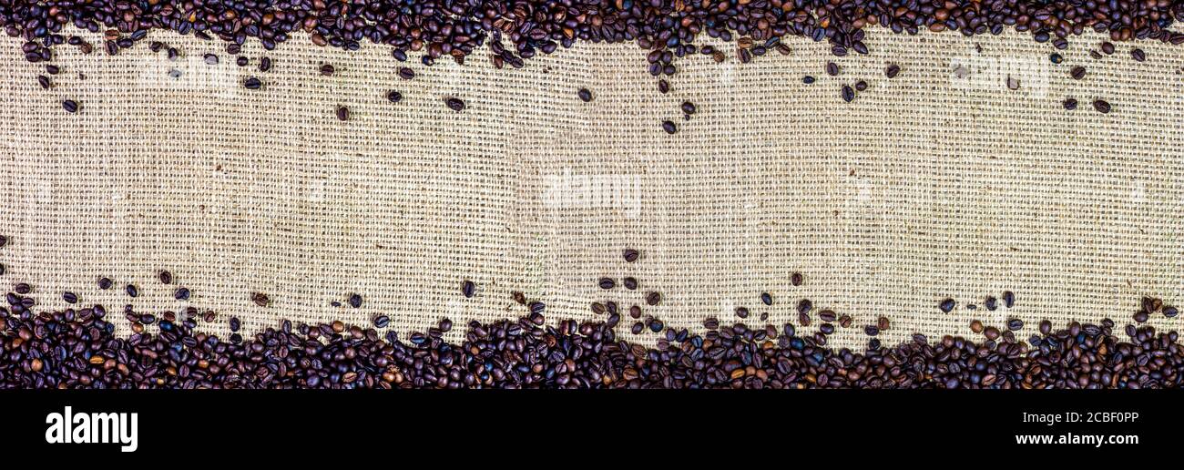 chicchi di caffè arrosto su tessuto di iuta, banner panorama di sfondo Foto Stock