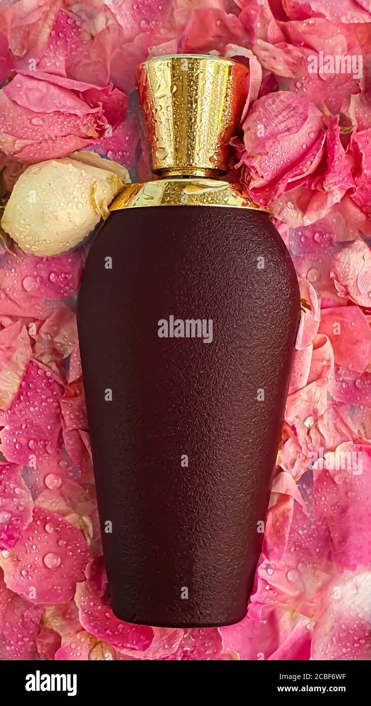 Bottiglia di velluto con profumo da donna. Circondato da petali di rosa su uno sfondo chiaro. Spazio di copia Foto Stock