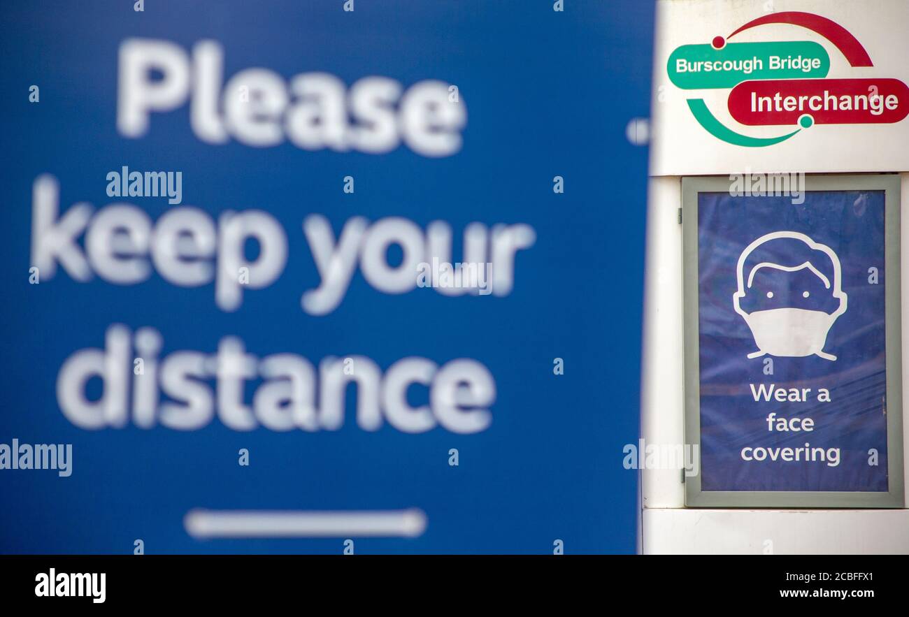 Si prega di mantenere la distanza e indossare un cartello di copertura viso presso Burns Cough Bridge Railway Tation, Lancashire UK Foto Stock