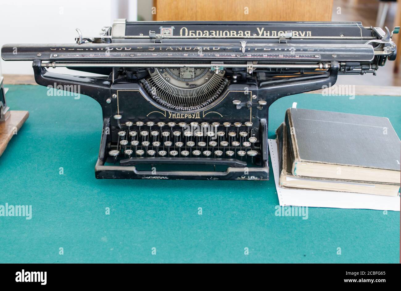 Ekaterinburg, Russia - Luglio 20 2019: Macchina da scrivere Underwood con lettere russe su un tavolo coperto di tessuto verde. Vicino a vecchi libri. Inscriptio Foto Stock