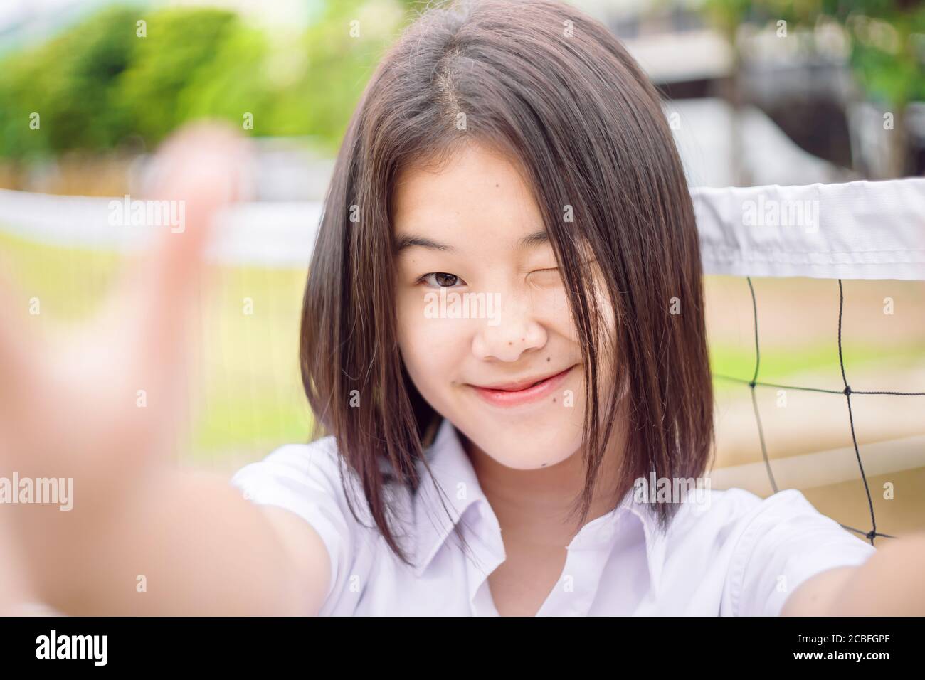 Carino asiatico studente ragazza winking occhio sorridente espressione selfie fotocamera, primo piano shot Foto Stock