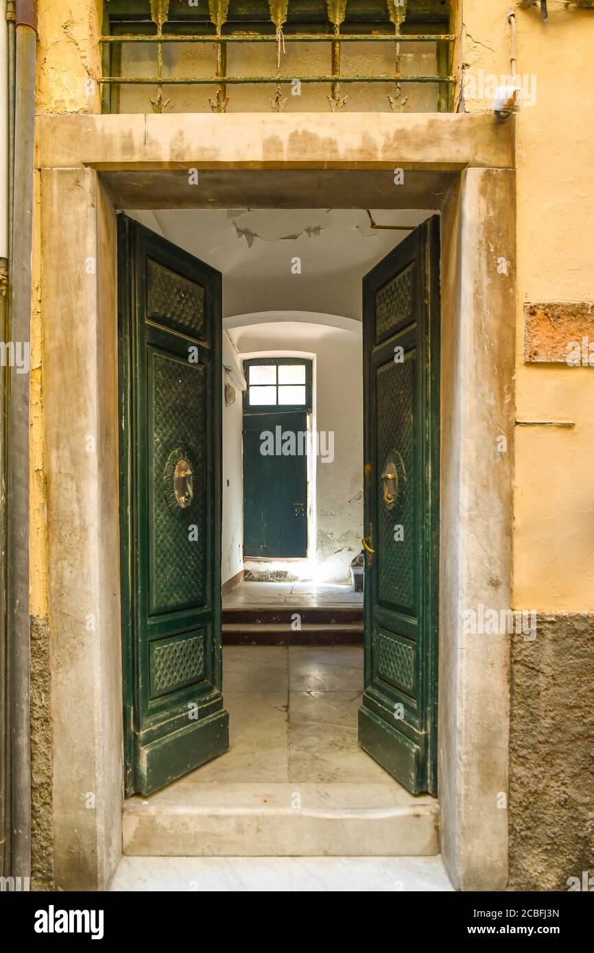 Il doppio ingresso di una tipica casa antica nel centro storico con porte in legno che si aprono sul corridoio con pavimento in marmo, Liguria, Italia Foto Stock