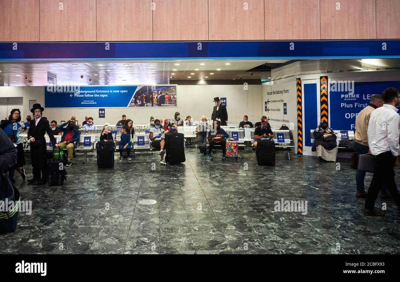 Passeggeri in attesa di treni sulla stazione di Euston durante il facemask Covid regolamenti Foto Stock