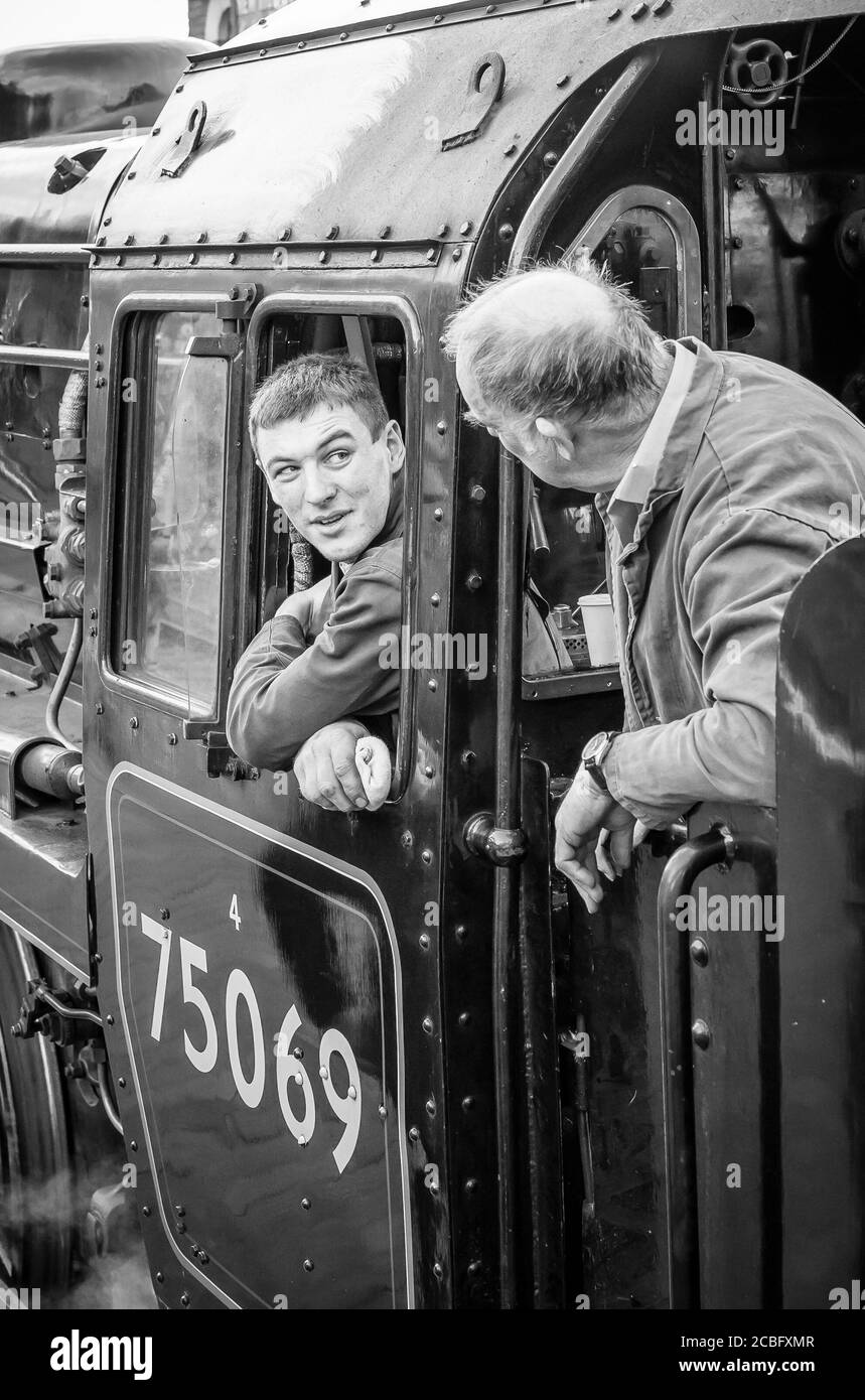 Treni a vapore vintage UK. Equipaggio monocromo del treno a vapore (autista del treno e vigili del fuoco) che chiacchiera insieme in un taxi della locomotiva, linea storica della Severn Valley Railway. Foto Stock