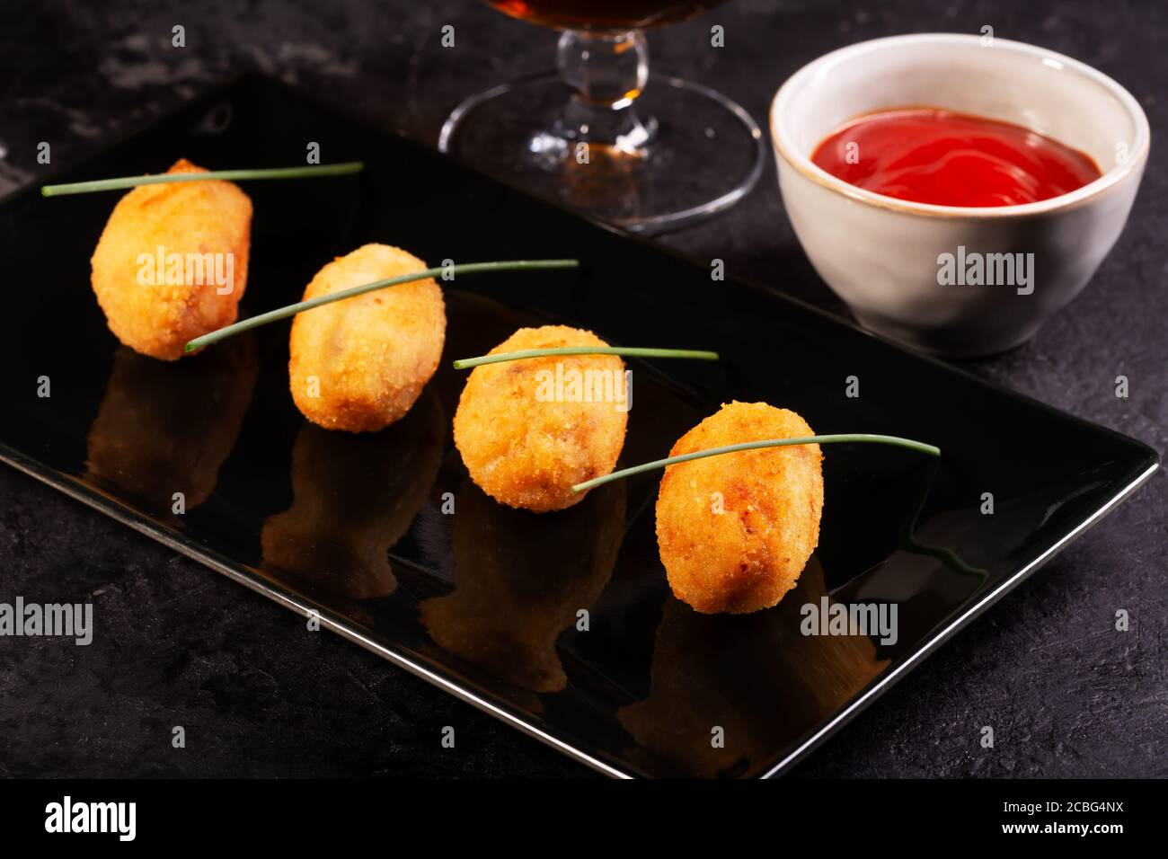 Crocchette di tapas, tradizionale spuntino spagnolo o francese con salsa rossa su sfondo scuro Foto Stock