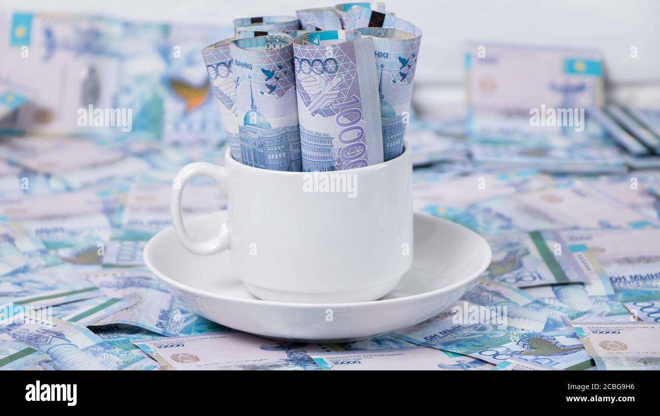 Soldi in una tazza di caffè. TENGE, la moneta nazionale del Kazakistan. Concetto, salario vivente. Economia, Asia centrale. Tagliare il budget, la corruzione, il calcio Foto Stock