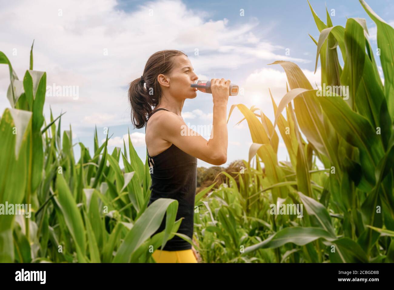 Donna sportiva che beve da una bottiglia d'acqua, reidratazione dopo l'esercizio. Foto Stock