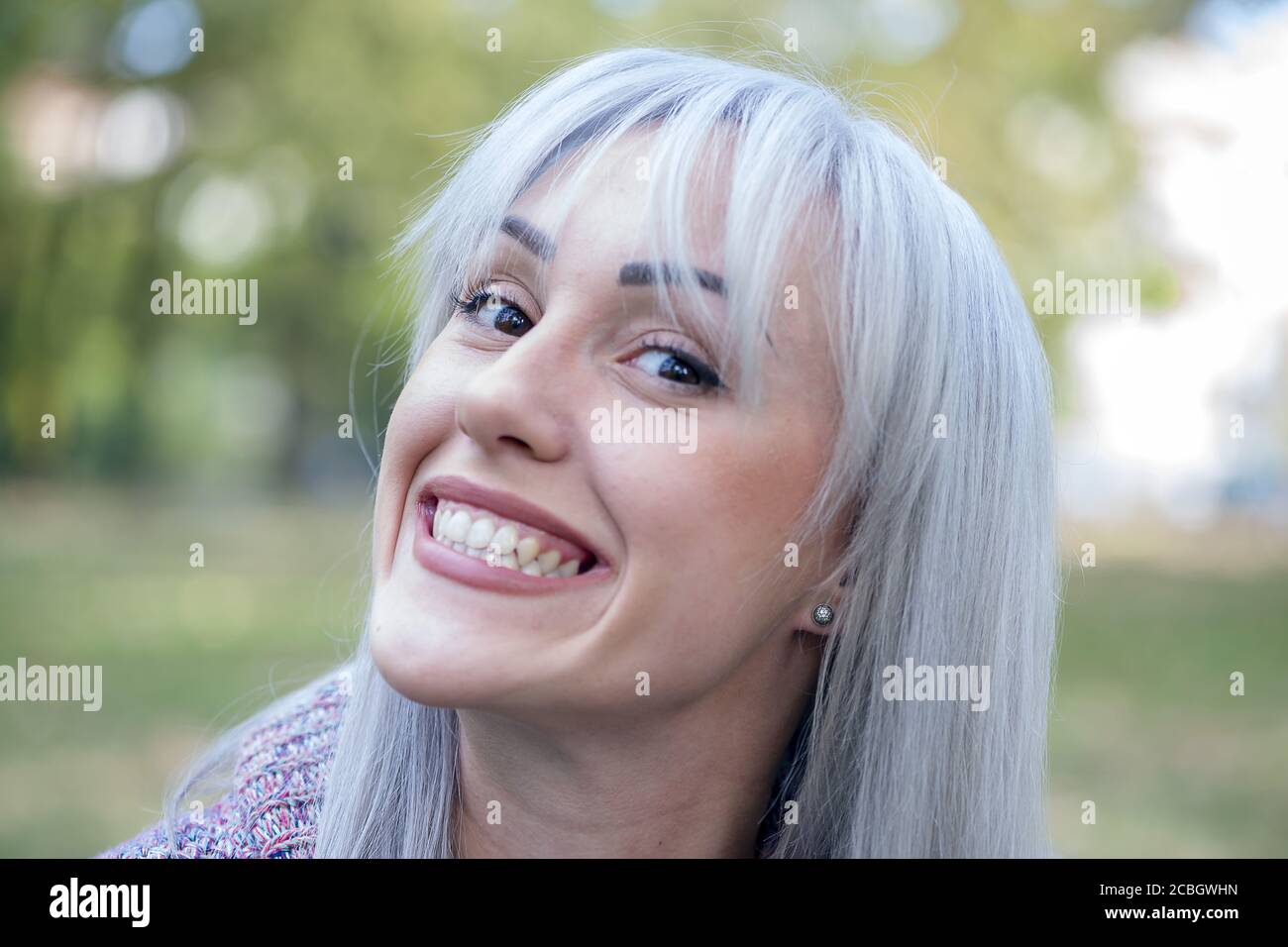 Ritratto all'aperto di una donna che fa volti divertenti. Capelli d'argento. Foto Stock