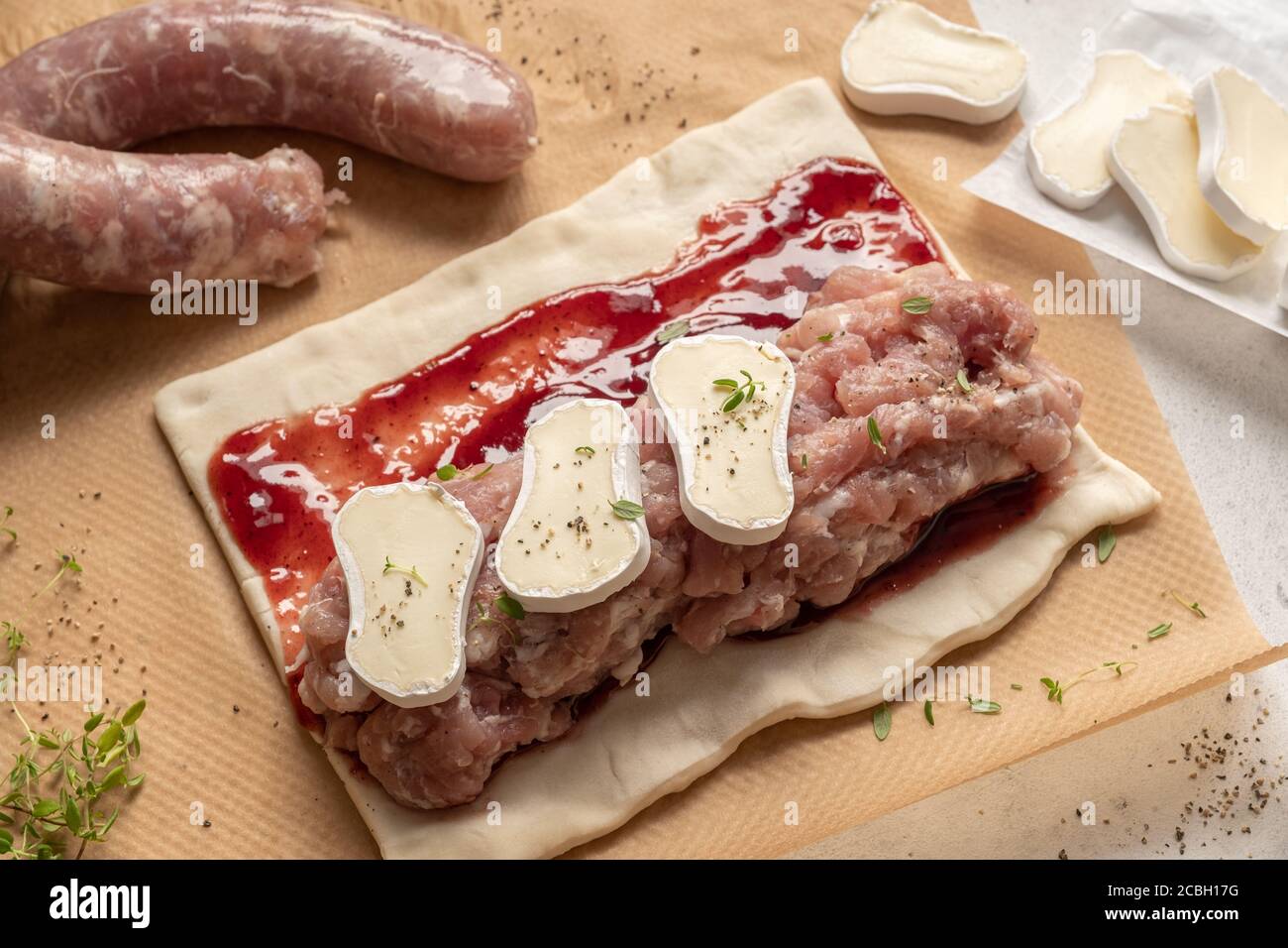 Involtini di salsiccia di tacchino di maiale crudo con formaggio brie e mirtillo rosso salsa in pasta sfoglia Foto Stock