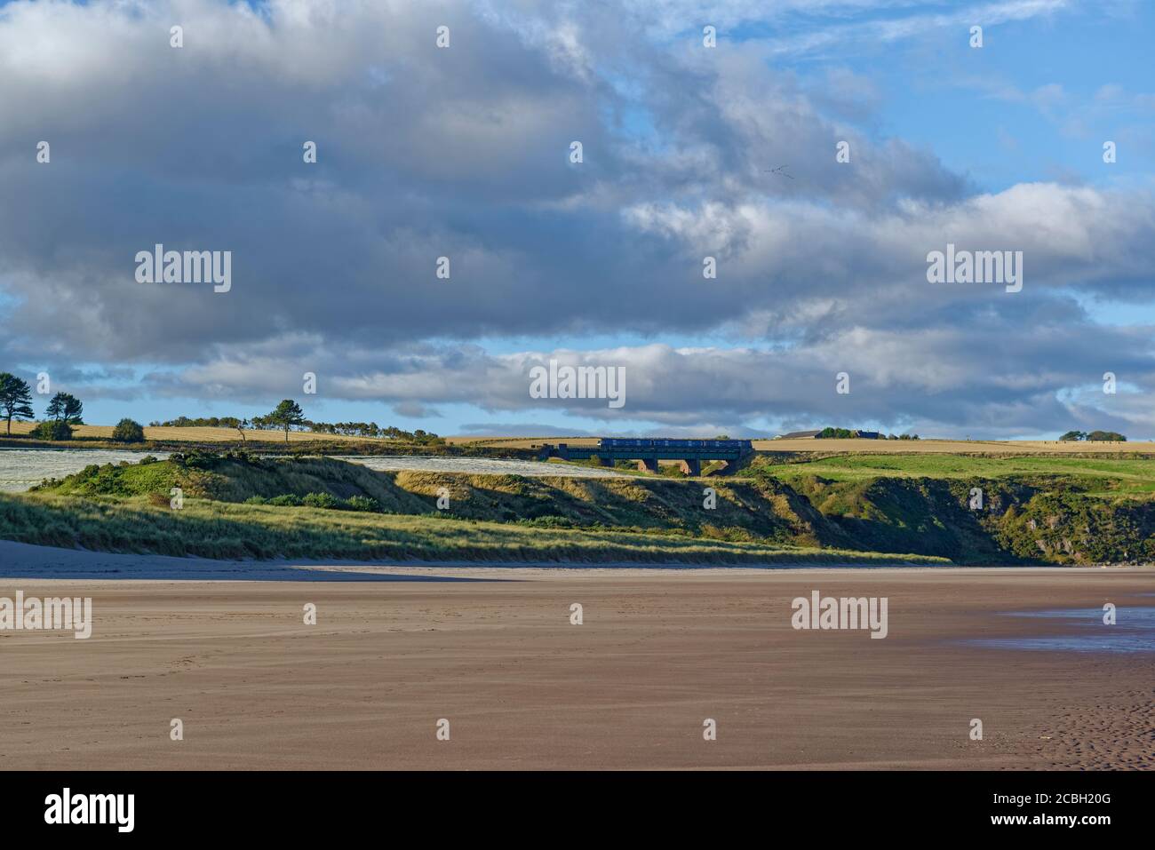 Un piccolo treno passeggeri che attraversa un ponte di coda in acciaio all'estremità settentrionale di St Cyrus Beach in un pomeriggio soleggiato a settembre. Foto Stock