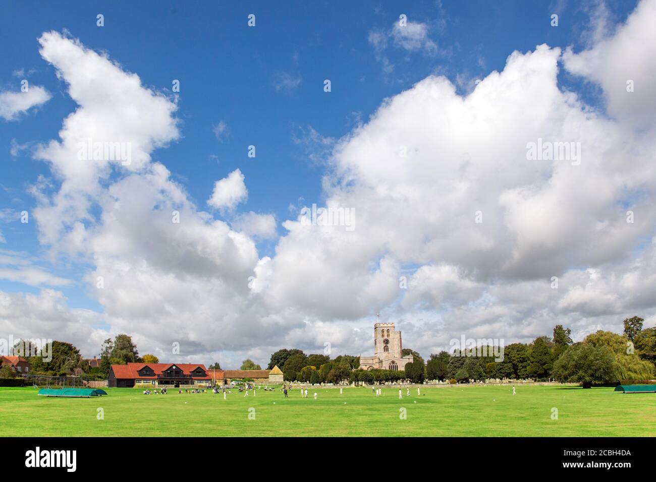 Junior partita di cricket giovani sul pittoresco prato della chiesa sede del club di cricket Thame Oxfordshire England con St Mary's. chiesa sullo sfondo Foto Stock