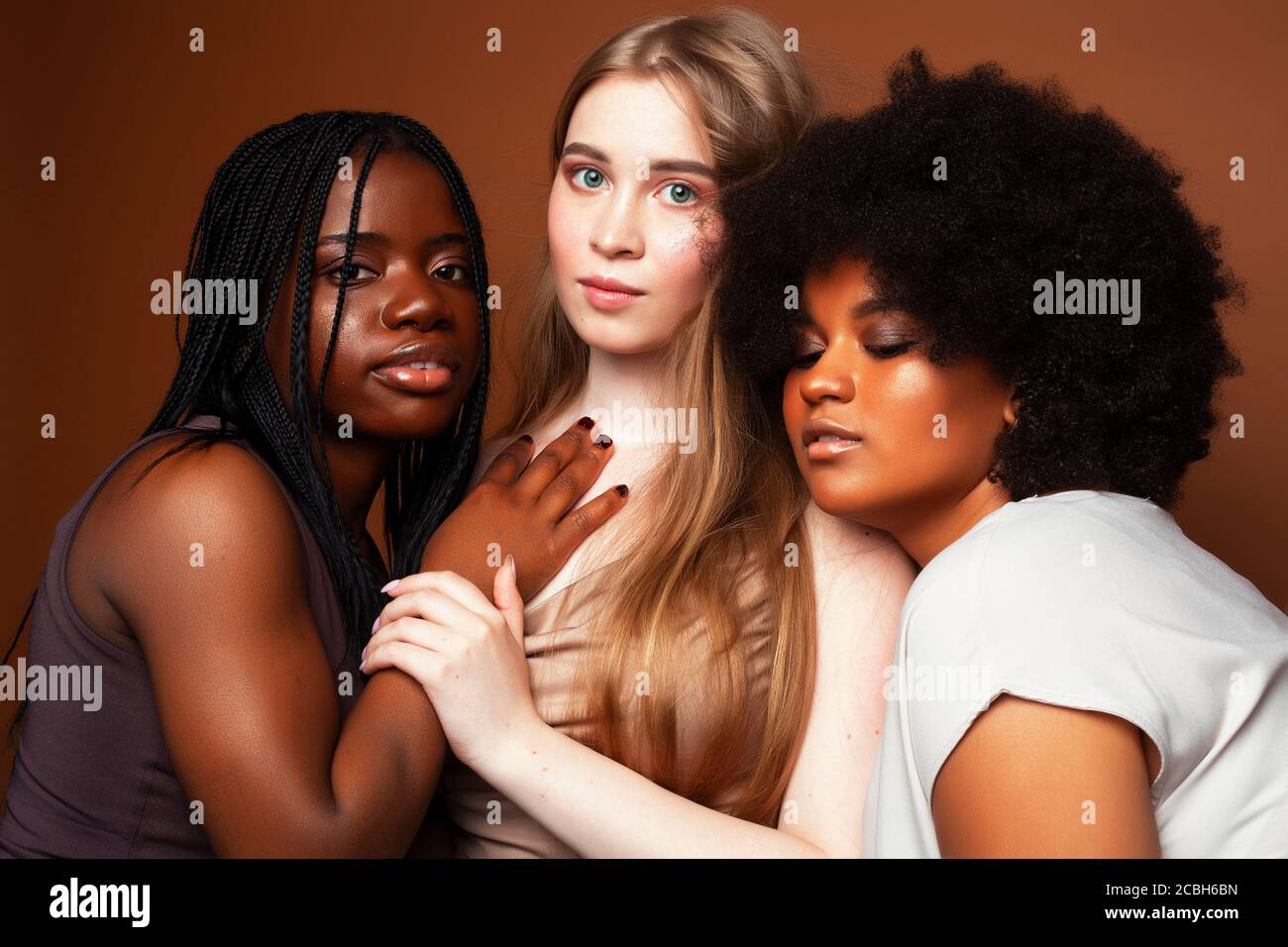 giovane bella caucasica, afro, donna scandinava che si pone allegro insieme su sfondo marrone, stile di vita diversa nazionalità persone concetto Foto Stock