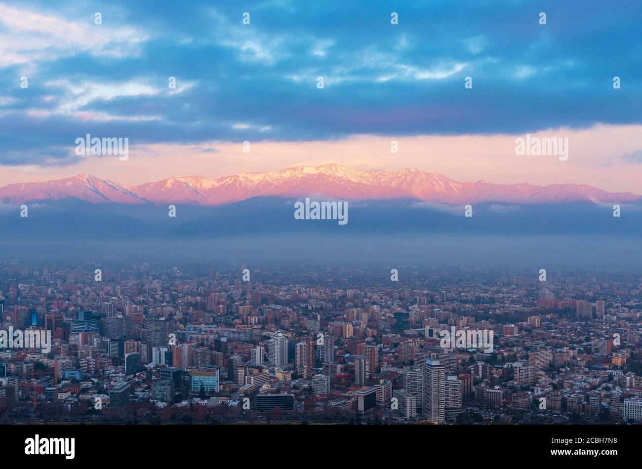 Skyline di Santiago del Cile al tramonto con le montagne illuminate delle Ande, Cile. Foto Stock