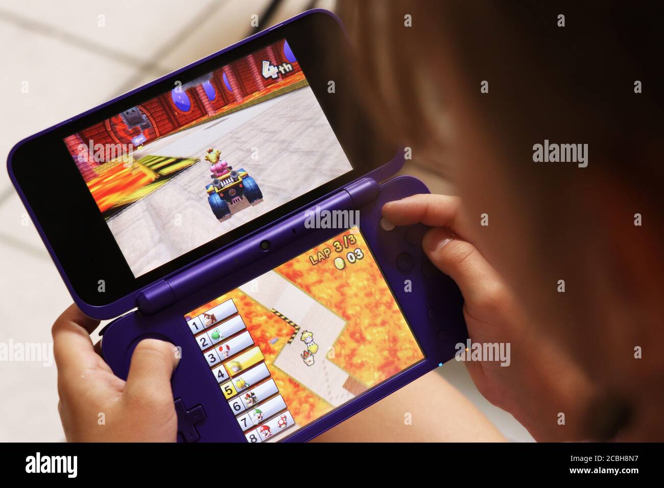 Bambino che gioca Mario Cart sul suo dispositivo Nintendo DS Foto Stock