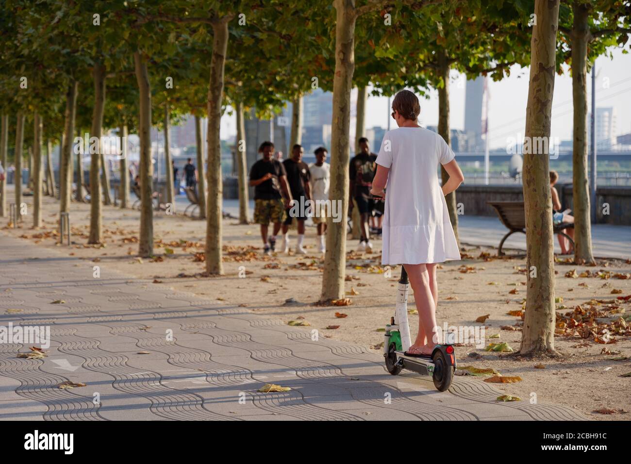 Scooter e-scooters di corsa dell'utente femminile, trasporto urbano trendy con il concetto di mobilità eco-amichevole condividendo Scooter elettrico, sulla pista della bicicletta. Foto Stock