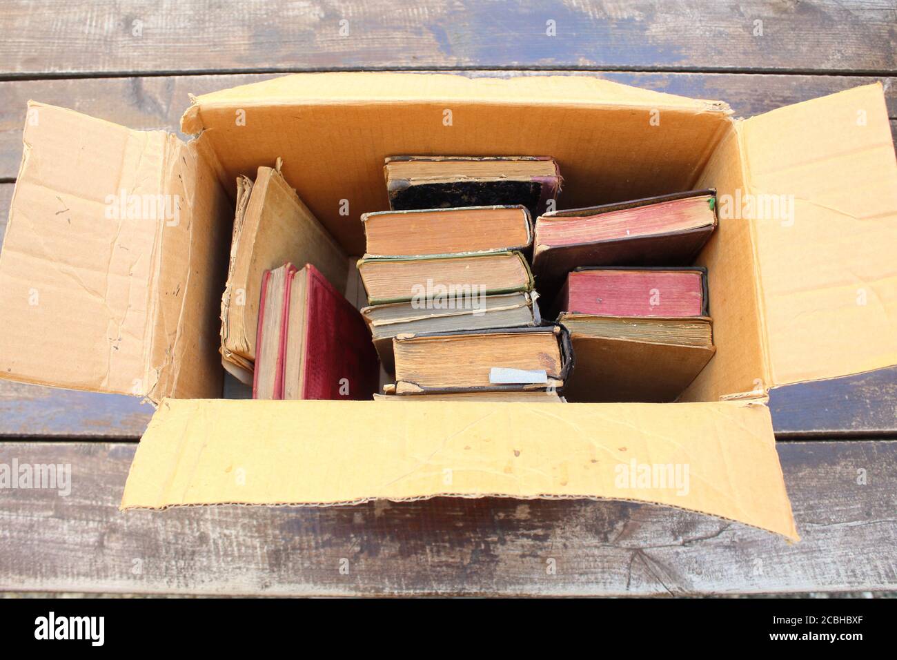 Scatola di cartone con vecchi libri sul tavolo primo piano Foto Stock