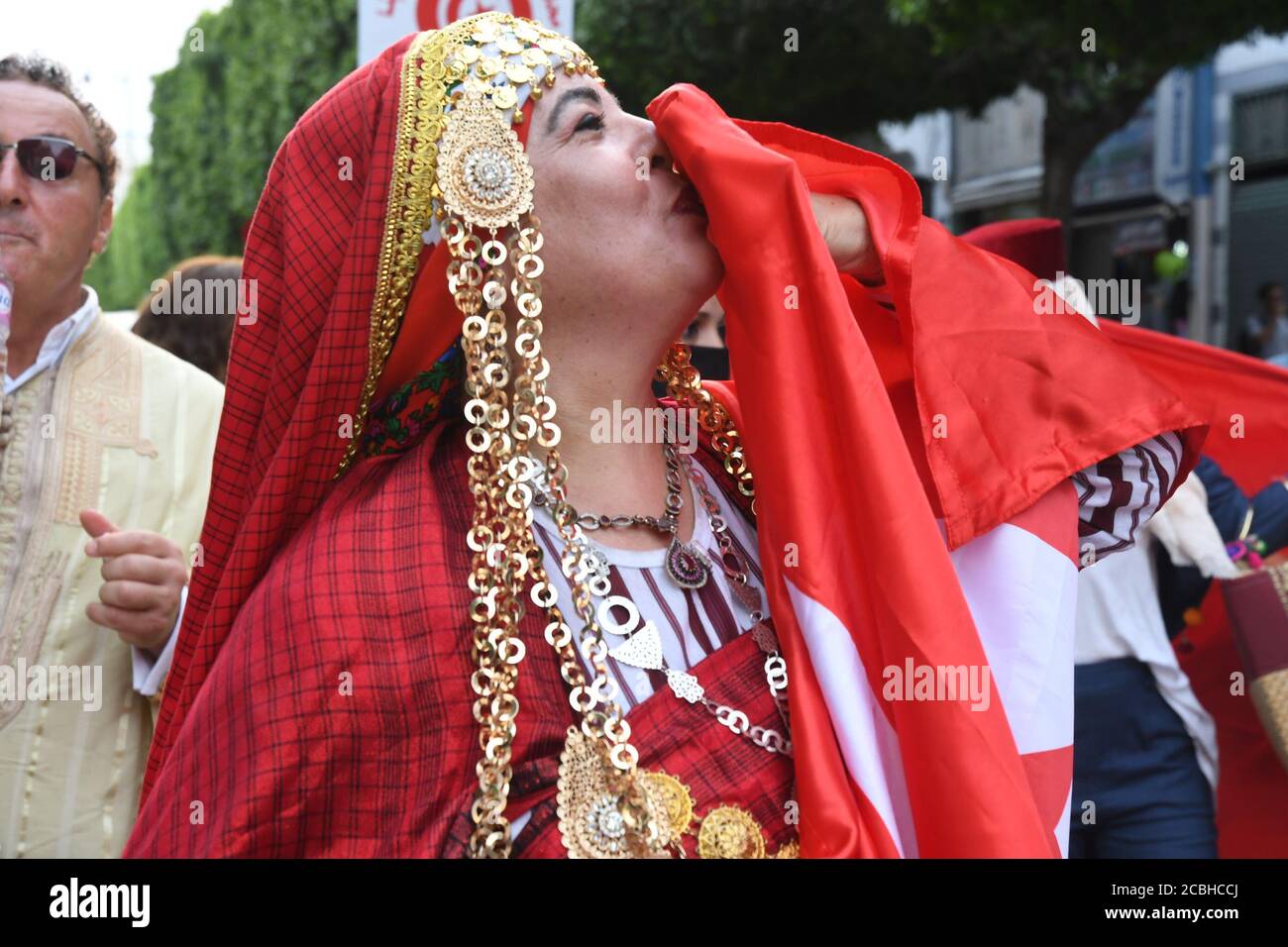Tunisi, Tunisia. 13 Agosto 2020. Una donna in costume folk tunisino bacia una bandiera nazionale tunisina durante le celebrazioni della Giornata Nazionale delle Donne nel centro di Tunisi, Tunisia, 13 agosto 2020. Credit: Adel Ezzine/Xinhua/Alamy Live News Foto Stock