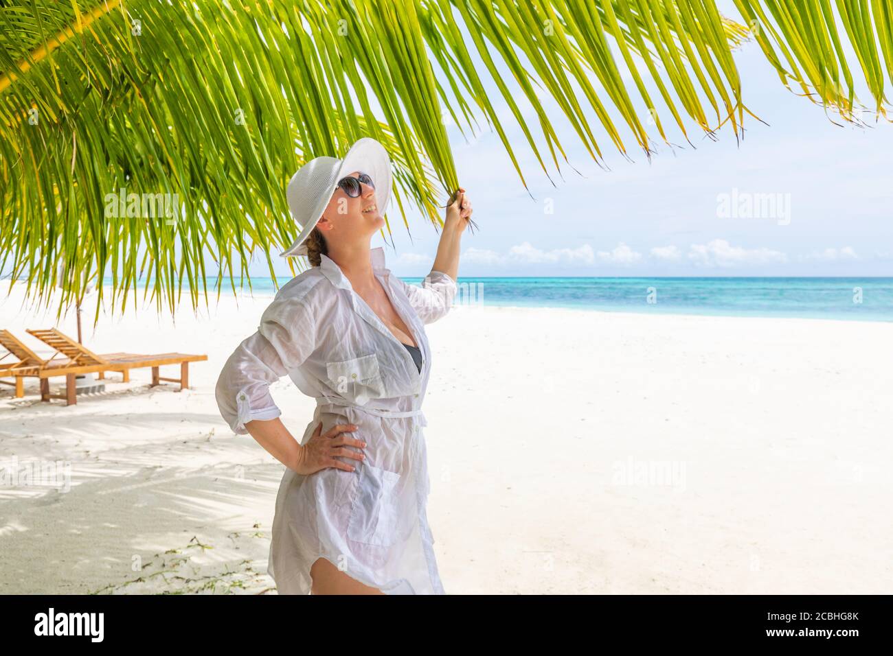 Donna che si rilassa sulla spiaggia, concetto di vacanza estiva, donna felice con abito bianco, cappello che si rilassa in amaca sulla spiaggia tropicale al tramonto Foto Stock
