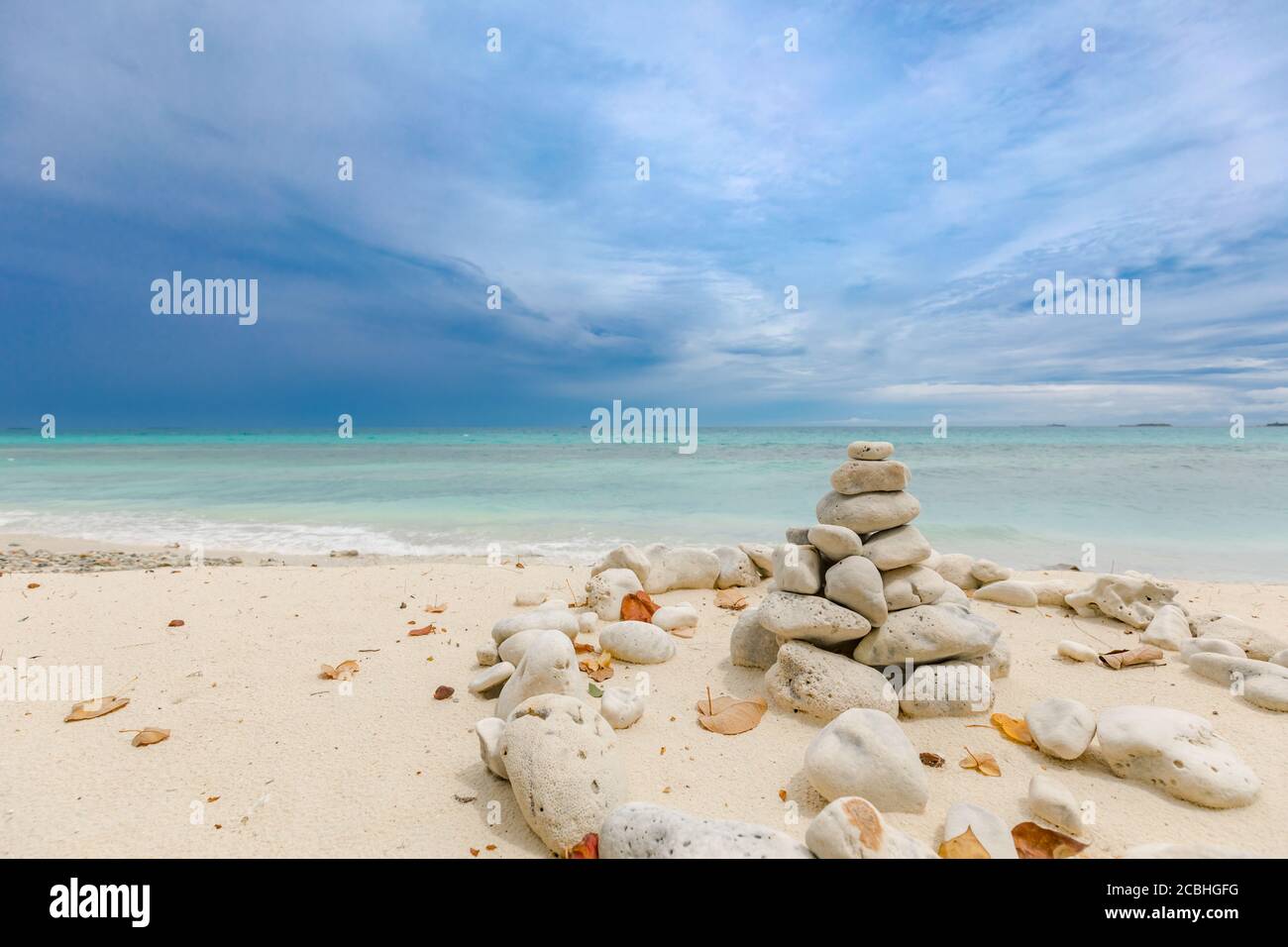 Pietre impilate sul mare al tramonto. Pietre equilibrate accatastate ad una torre sulla spiaggia, nuvole con cielo drammatico Foto Stock