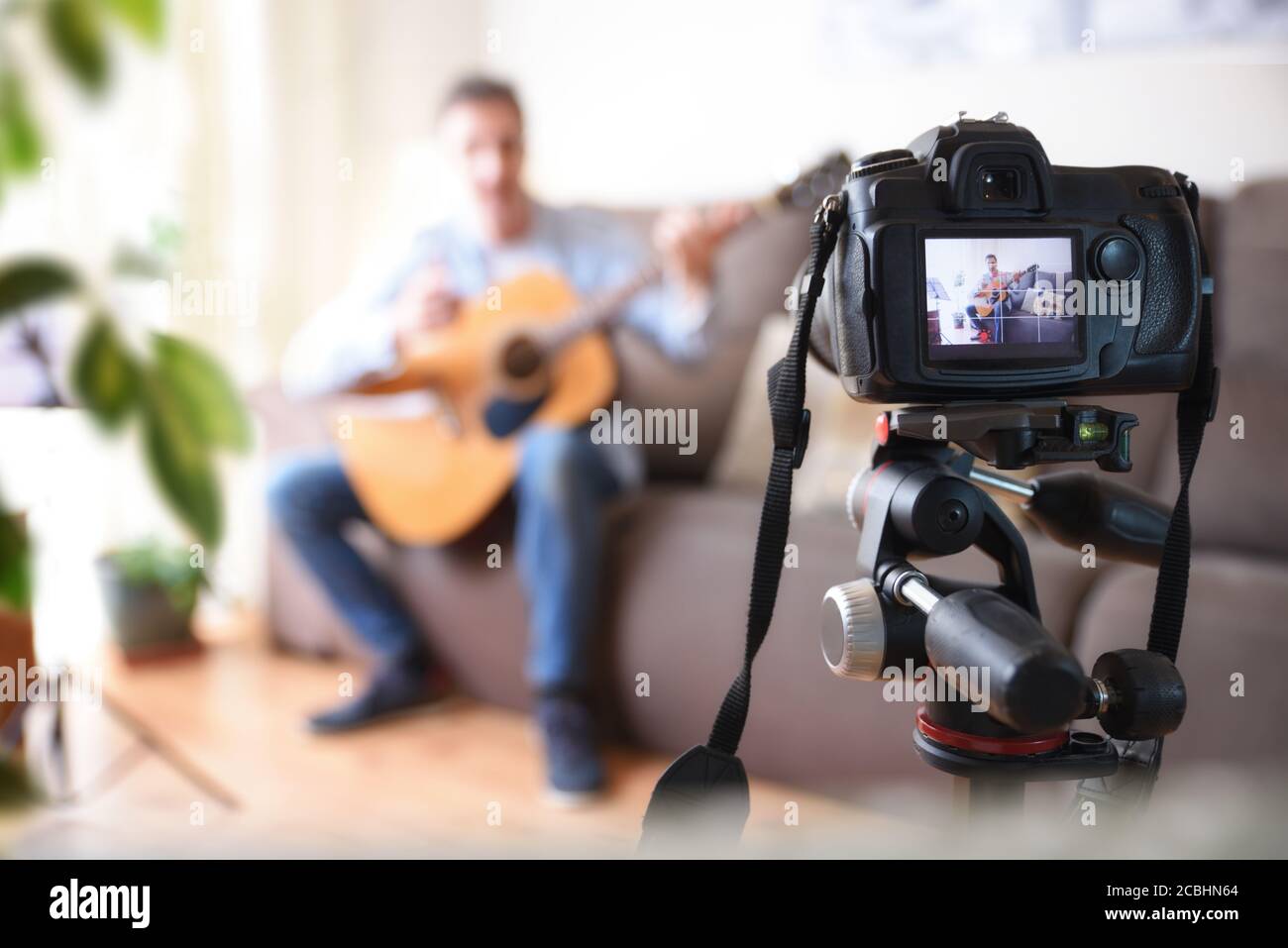 Telecamera di registrazione video blogger facendo una recensione di una chitarra nel soggiorno Foto Stock