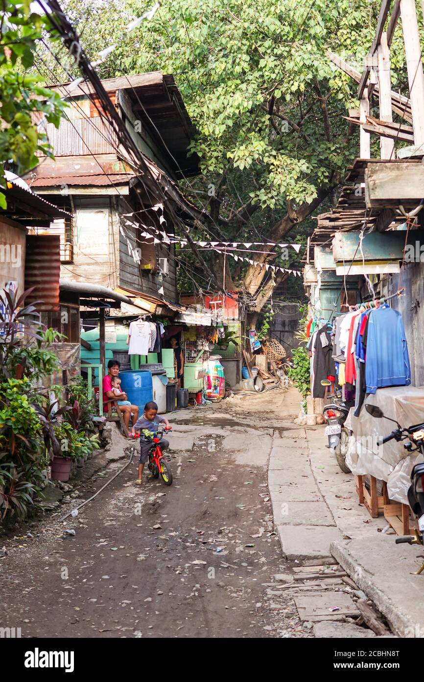Cebu / Filippine - 10 luglio 2019: Piccolo ragazzo in bicicletta colorata in strada sterrata nel quartiere povero della città di Cebu Foto Stock