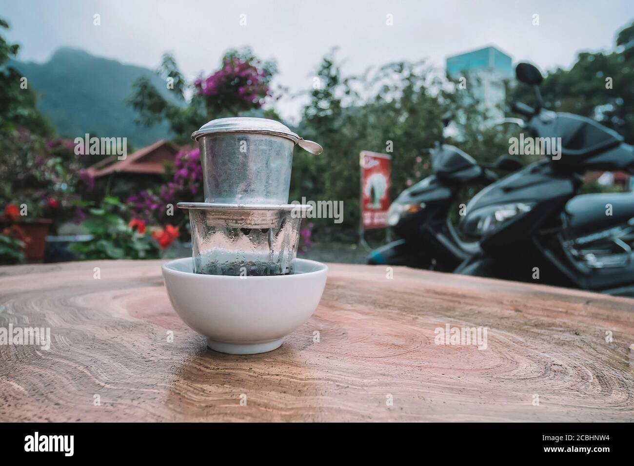 Stile caffè vietnamita, caffè gocciolante, acqua goccia su caffè macinato in filtro inox con sfondo tavolo in legno. Vista dall'alto e spazio per la copia Foto Stock
