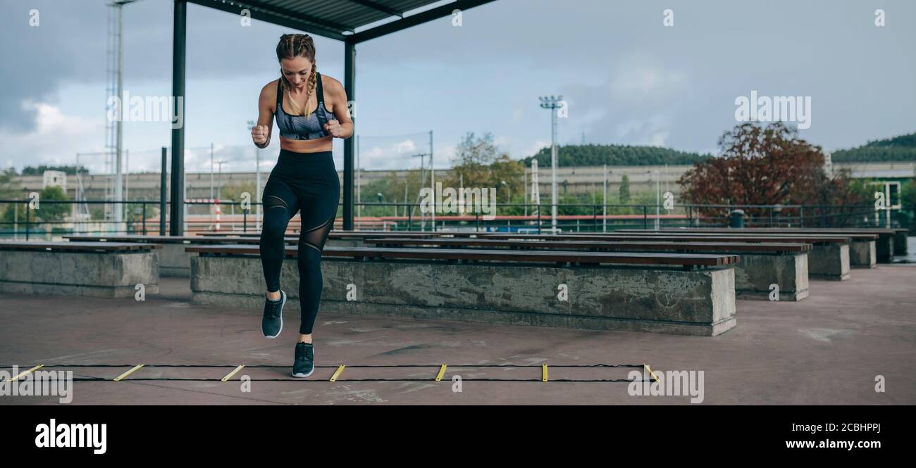 Sportive saltando su una scaletta di agilità Foto Stock