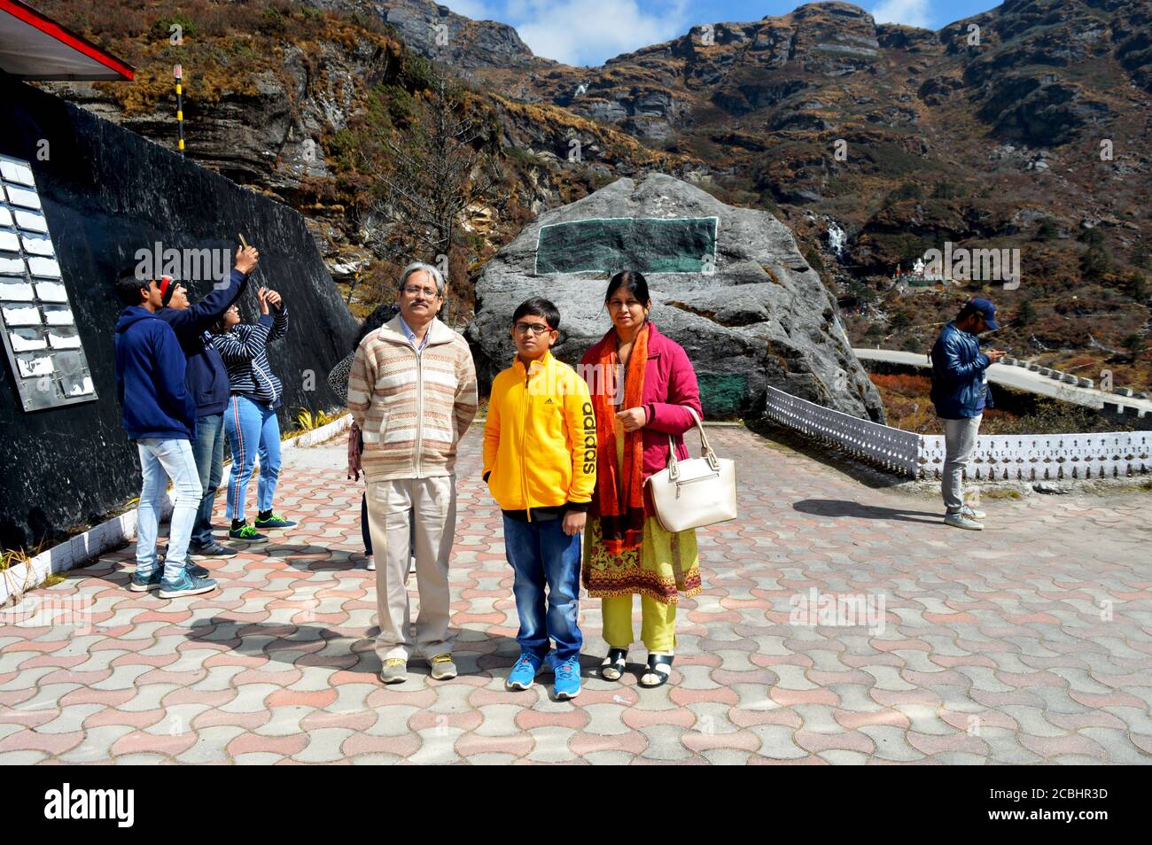 Una famiglia turistica indiana di padre, madre e figlio in posa davanti alla roccia commemorativa di Baba Harbhajan Singh Sahib Mandir nel passo di Nathula di Sikkim Foto Stock