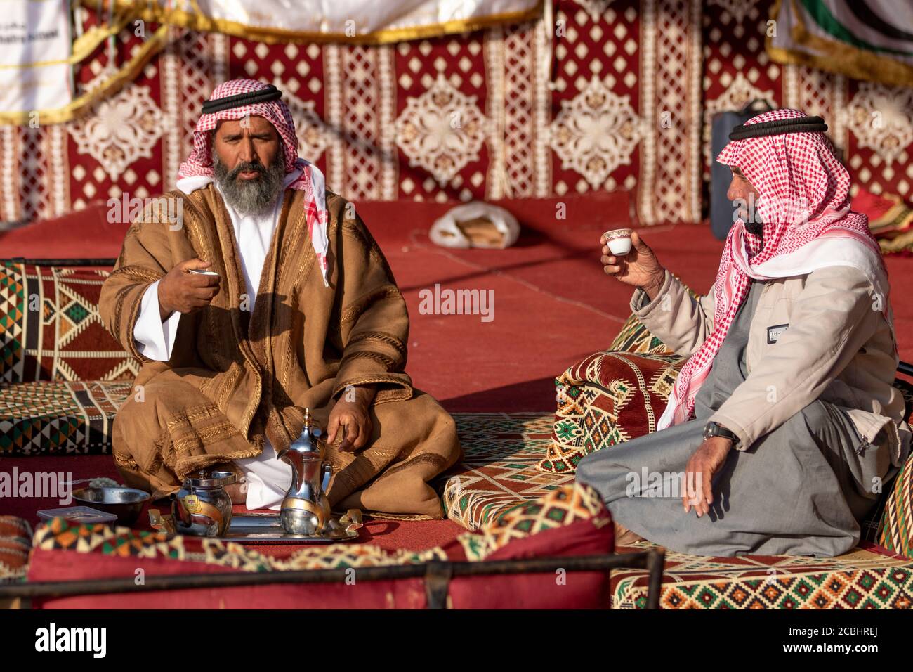 Un uomo arabo anziano che offre caffè ad un ospite in la sua tenda Foto Stock