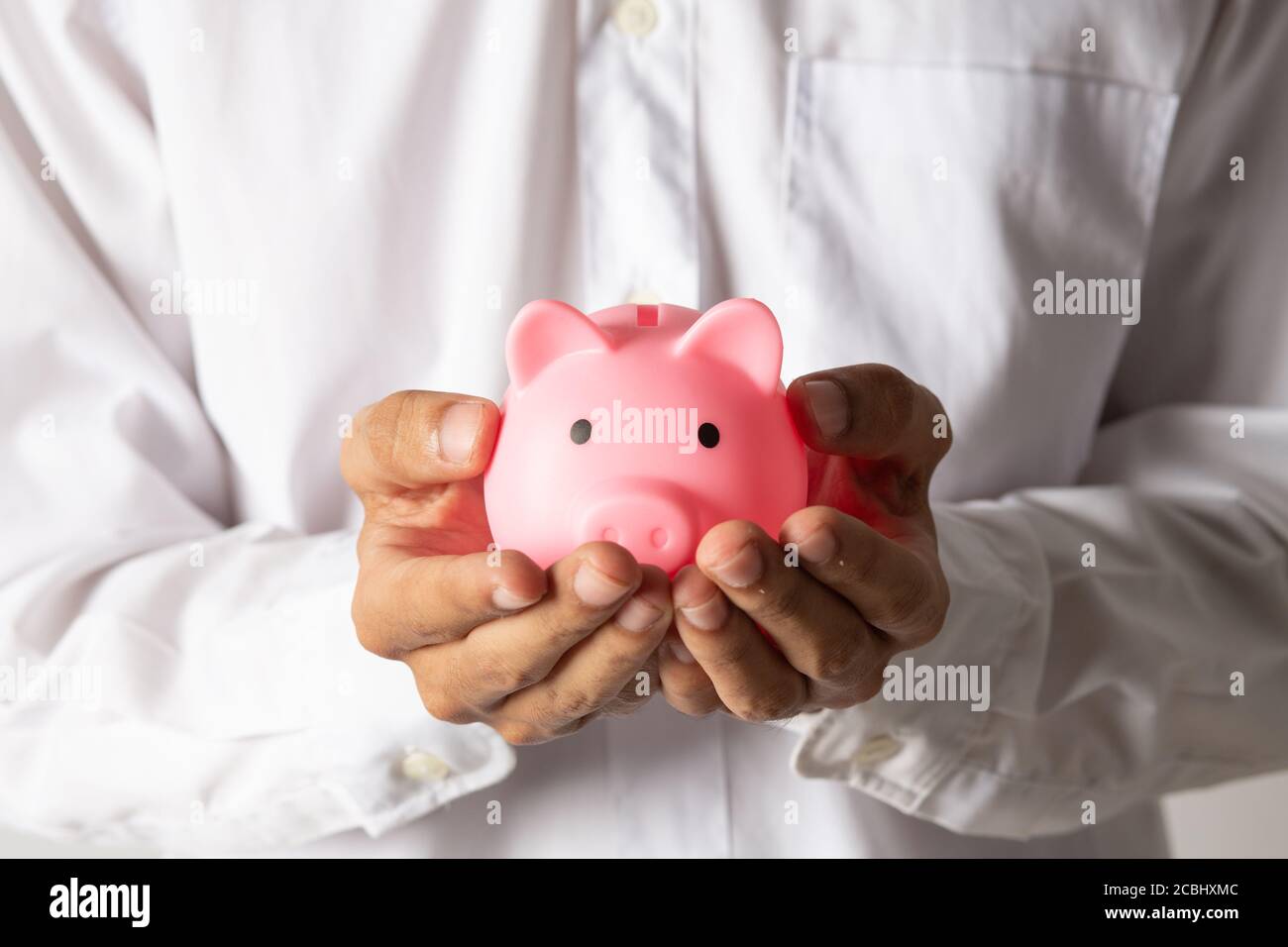 Mano di capretto che tiene moneta messo in banca piggy con pila di soldi crescente crescita che risparmia denaro, concetto di investimento per il piano di libertà finanziaria, business. Foto Stock