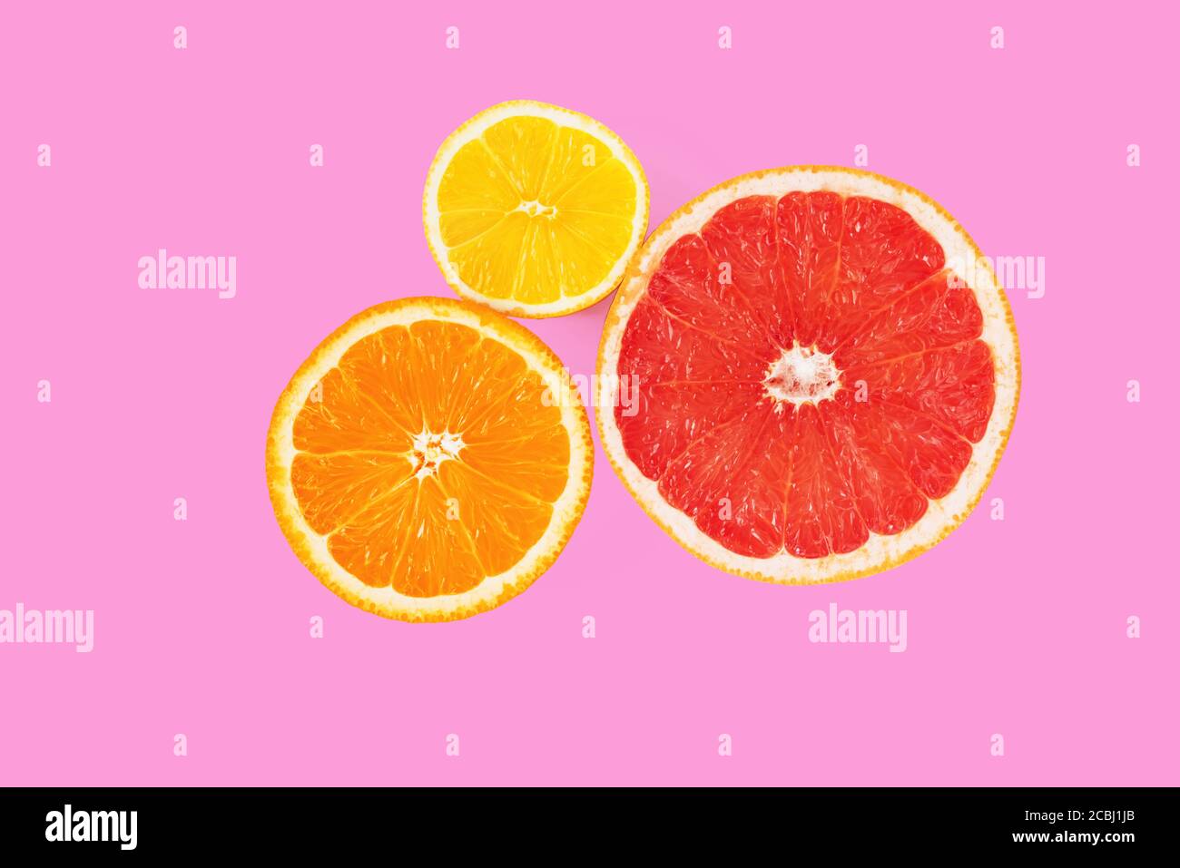 Metà di arancio, pompelmo rosa e limone su sfondo rosa. Vista dall'alto della sezione trasversale degli agrumi. Composizione minima. Primo piano Foto Stock