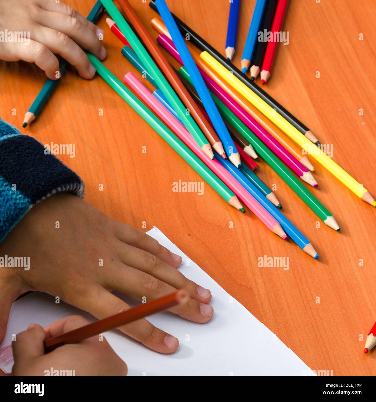 Disegno a mano del bambino su un foglio bianco di carta con matite colorate. Concetto di educazione, svago e attività per bambini. Primo piano Foto Stock