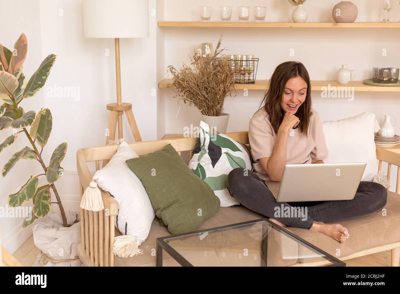Donna allegra che usa il computer portatile sul divano Foto Stock